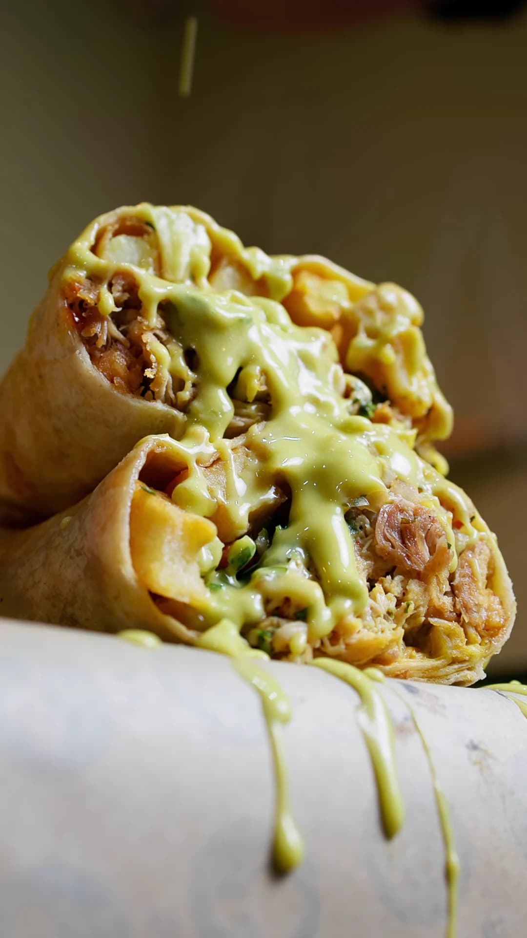 Loaded Burgerito burrito halves finished with green sauce.