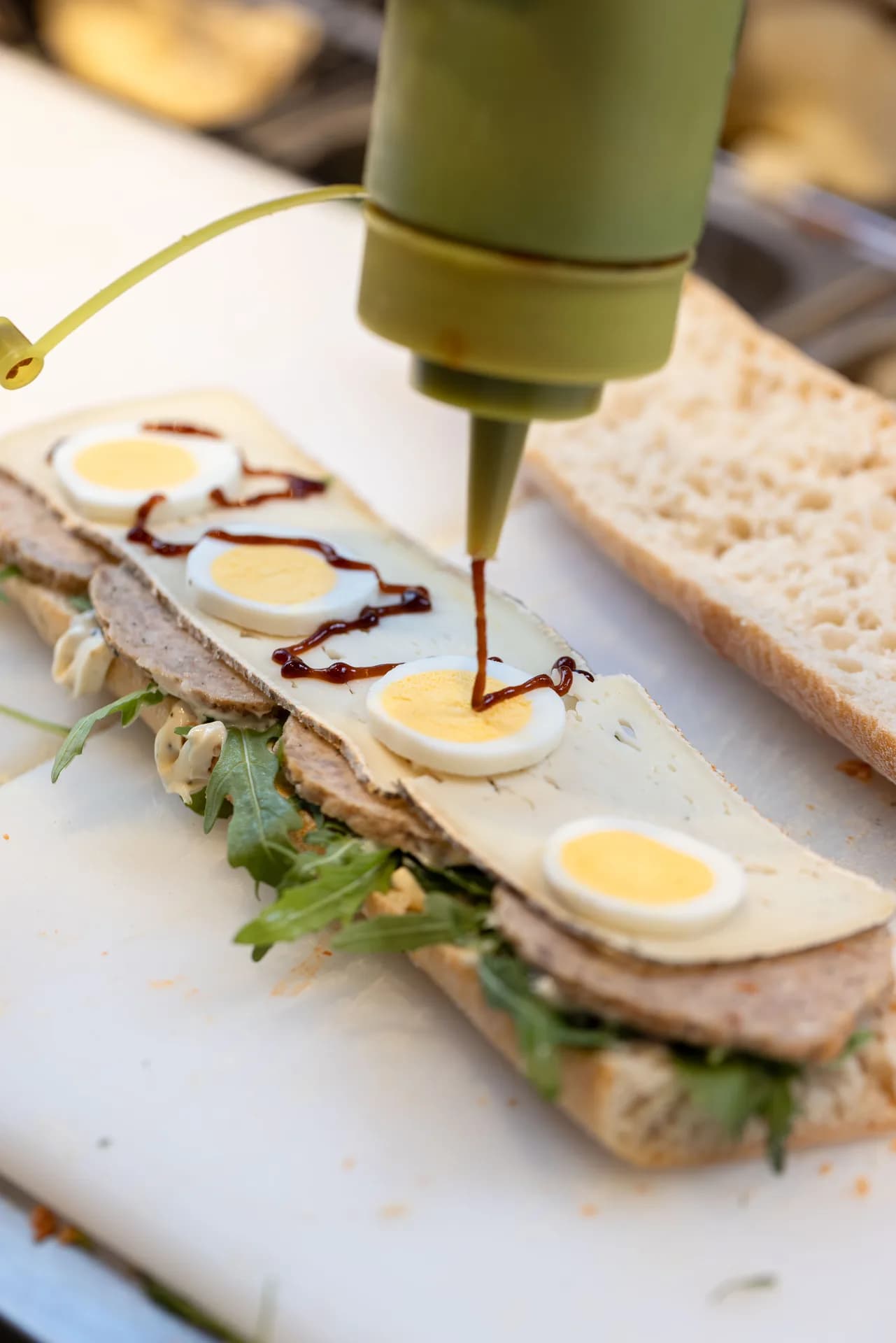 Finition d’un sandwich à l’œuf Jeanbon sur le plan de préparation.