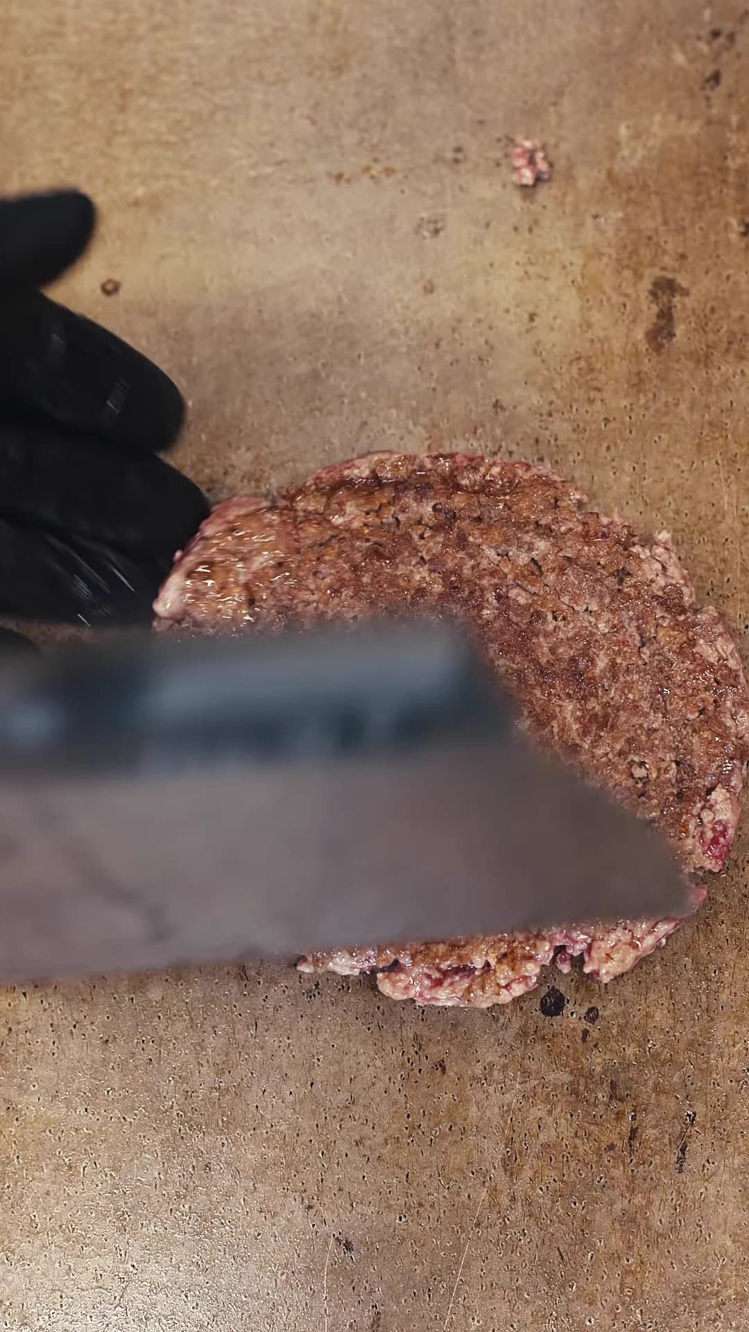 Burger patty being pressed on the griddle at Oresto.