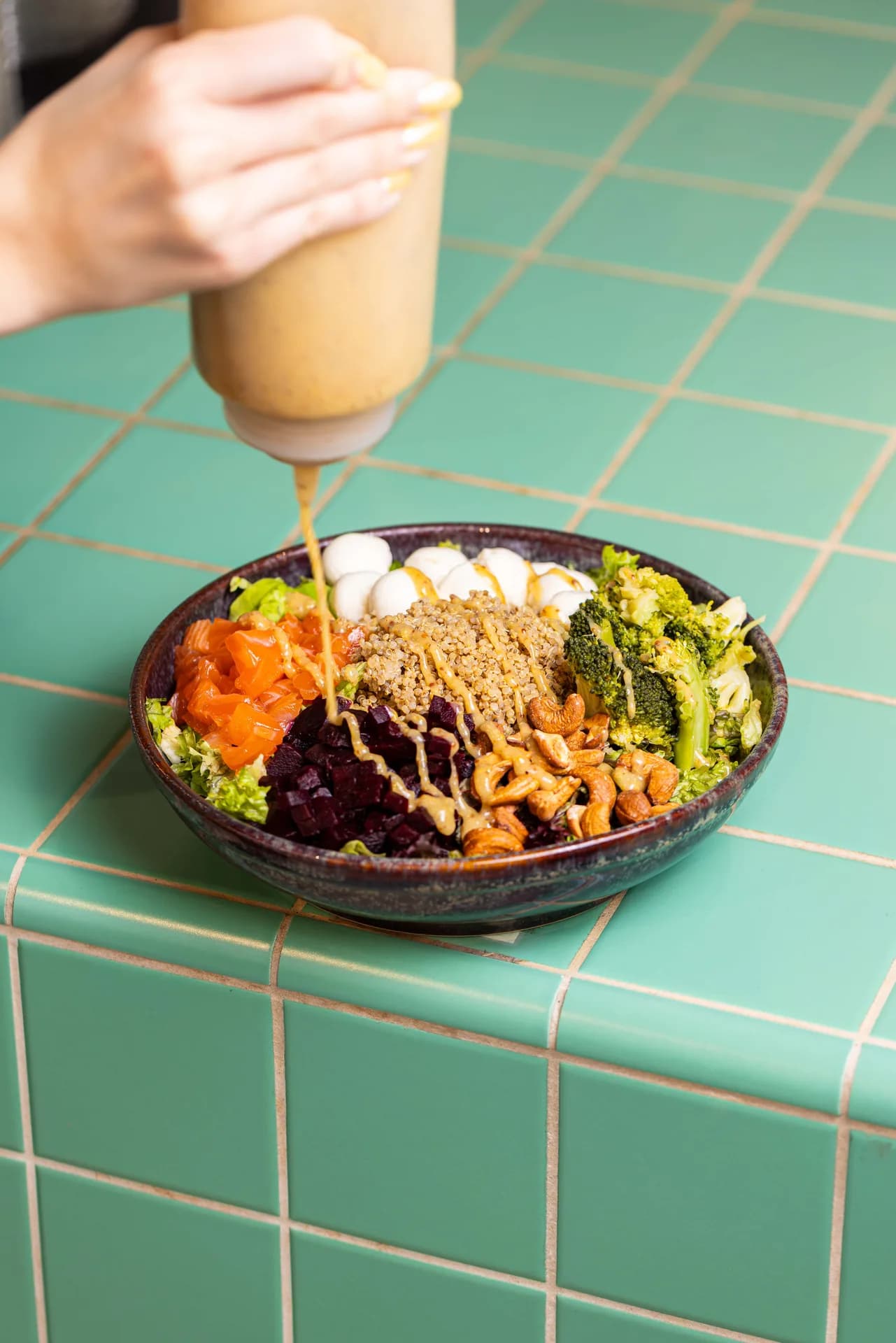 Dressing poured over a colourful Superbowls grain bowl.