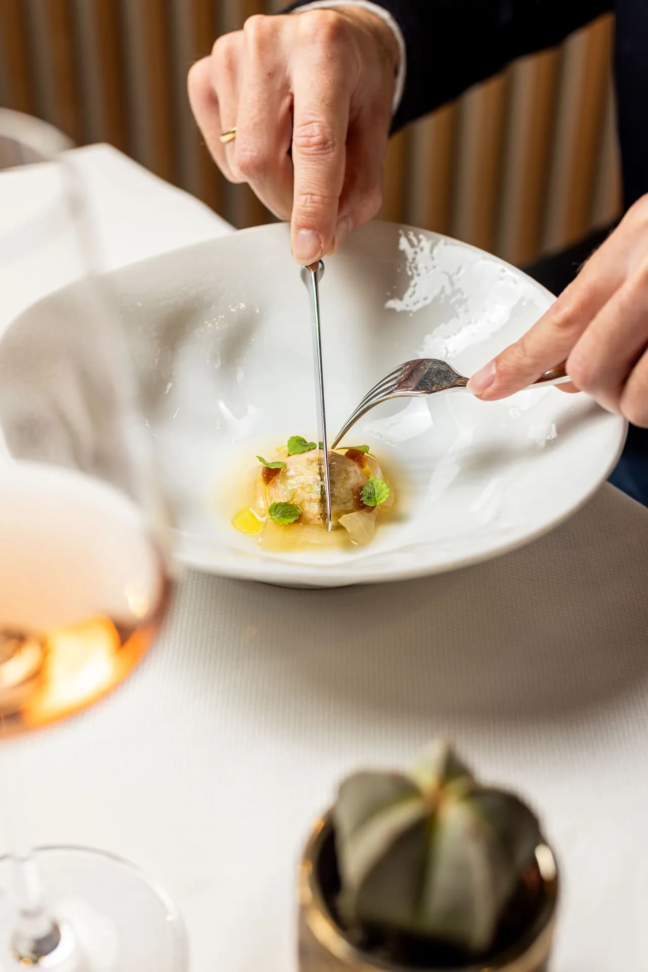 Guest cutting into a plated fine-dining course at Uma.